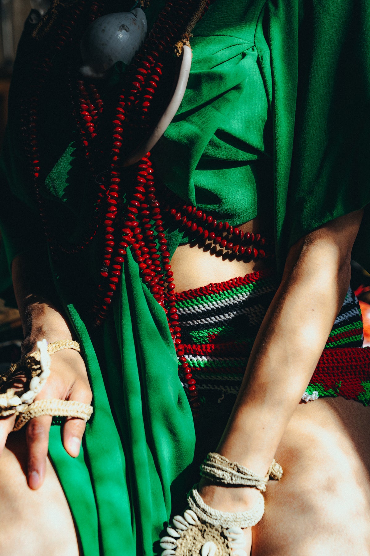Close-up of green fabric, red beads and shell bracelets in the Sexy Talar shoot.