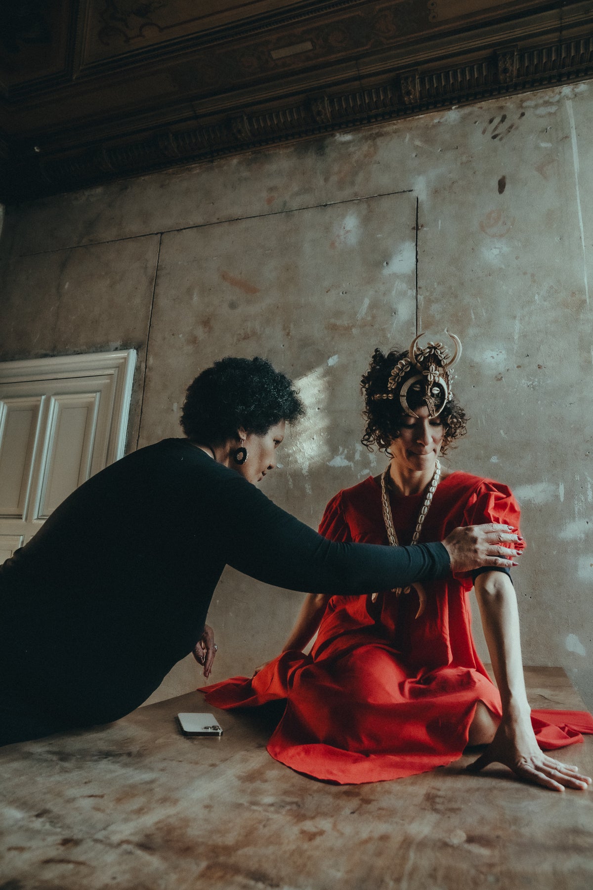 A stylist adjusts the sleeve of the red Sexy Talar during a photoshoot.